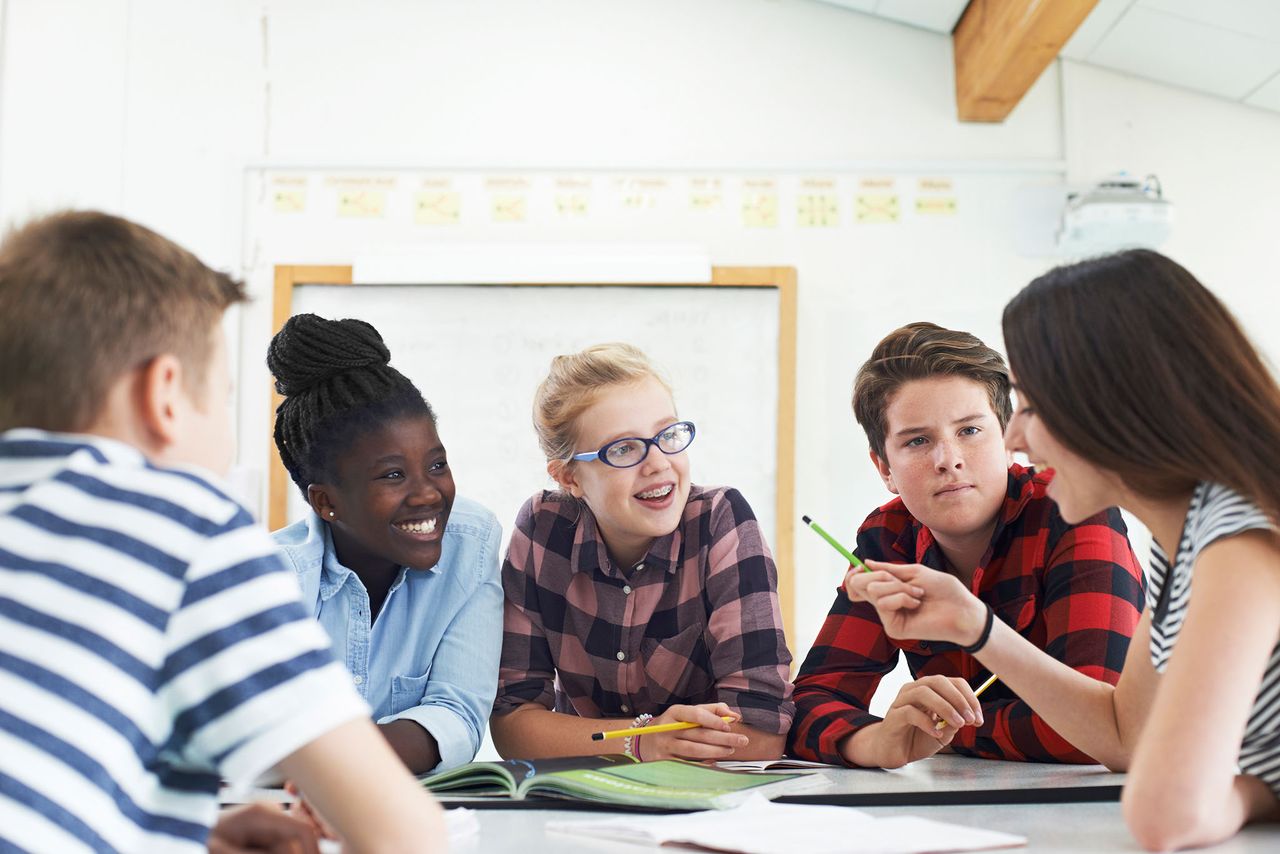 Teenage students collaborating on a project around a classroom table